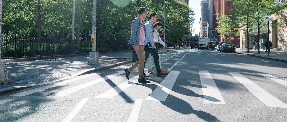 People walking across a zebra crossing on a sunny street