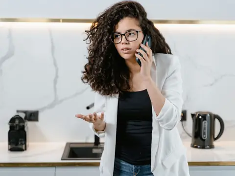 A woman on a phone call in her kitchen