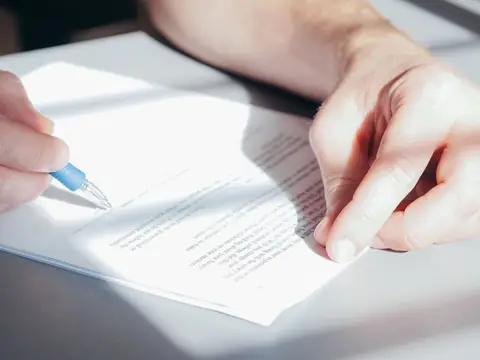 A hand writing on a printed page with a pen