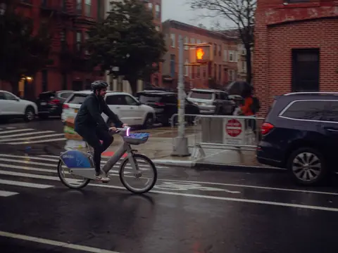 A cyclist riding through a wet city intersection