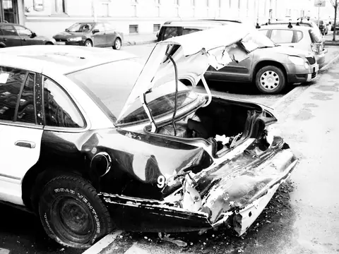 A car with a crushed rear end parked on a city street