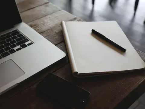 A notebook and a pen beside a laptop
