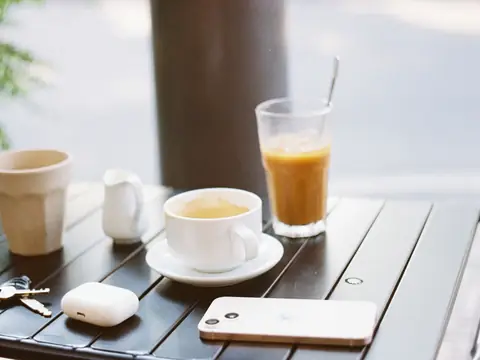 A phone, car keys and coffee on a cafe table