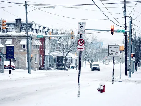 A snowy intersection with traffic lights and street signs