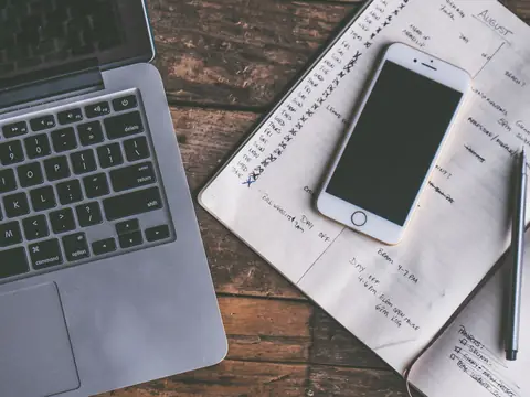 Handwritten notes beside a phone and a laptop