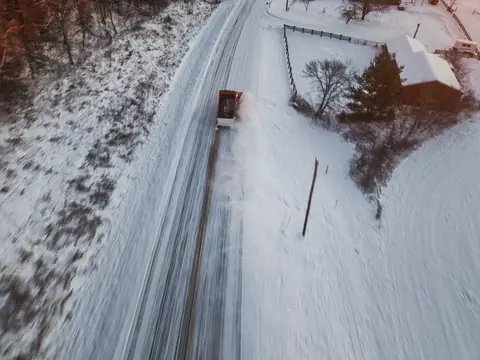 A snowplow clearing a rural road, seen from above