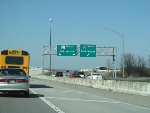 Cars and a school bus on I-69 in Indiana under signs for Fort Wayne