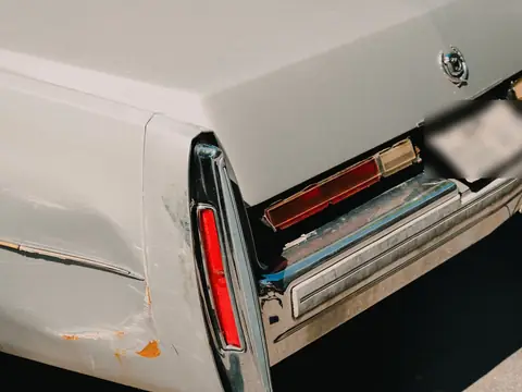 A scraped and dented rear corner of a white car