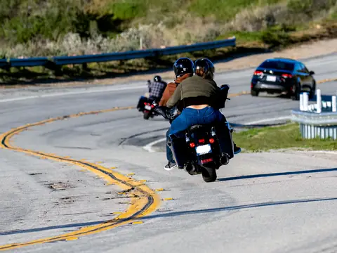 Two riders on a motorcycle leaning into a curve with double yellow lines