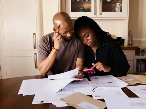 Two people going through bills at a kitchen table
