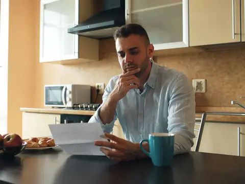 A man reading a letter at a kitchen table