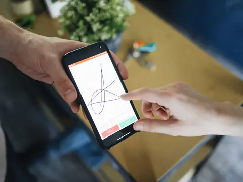 Hands signing a form on a phone screen