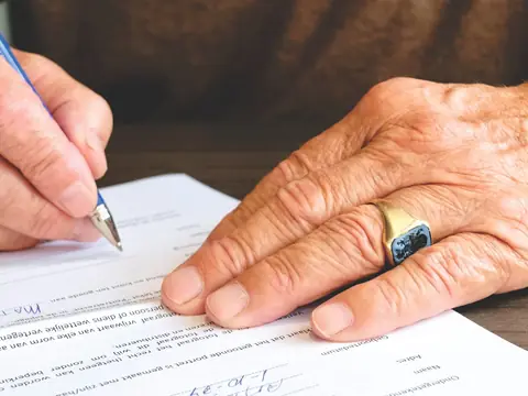 A hand signing a printed page with a pen