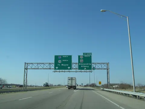 A semi truck and cars on I-69 in Indiana under signs for Fort Wayne
